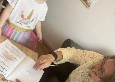 Leah signing a book for a very happy little girl