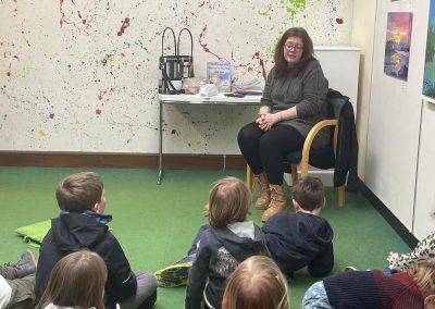 Leah reading a book to a group of children, they are very interested.