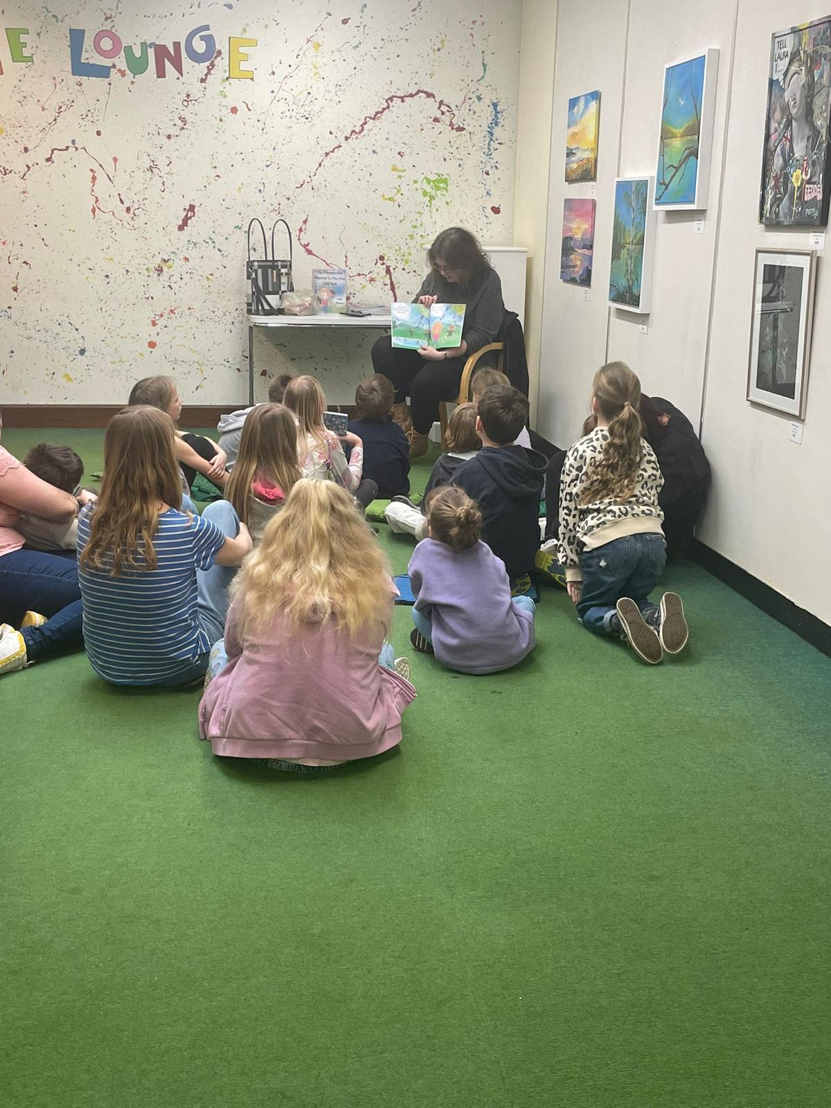 online-university-14 Leah reading her book the princess who wanted to play hide and seek. To a group of young children aged about 3-6 years old. they are all sitting listening intently.